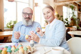 Contemporary aged couple preparing painted eggs for Easter before the holiday