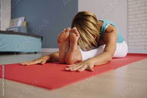 Details of the hands of a young woman practicing yoga on a white brick wall. soft focus on foot