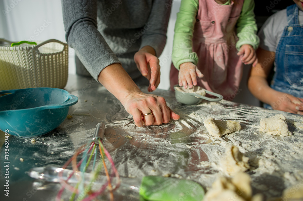 Mom teaches two little daughters to cook from dough. Mom teaches two little daughters to cook from dough.