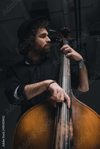 bottom view of handsome musician playing contrabass