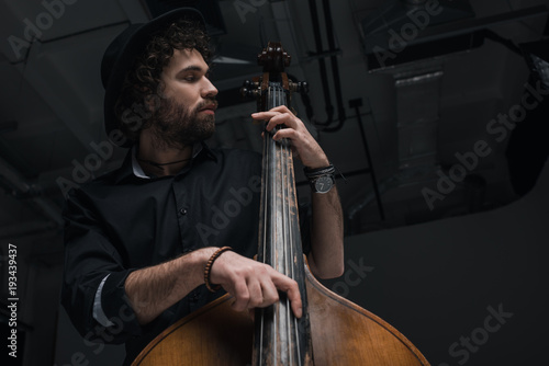 bottom view of young handsome musician playing contrabass photo