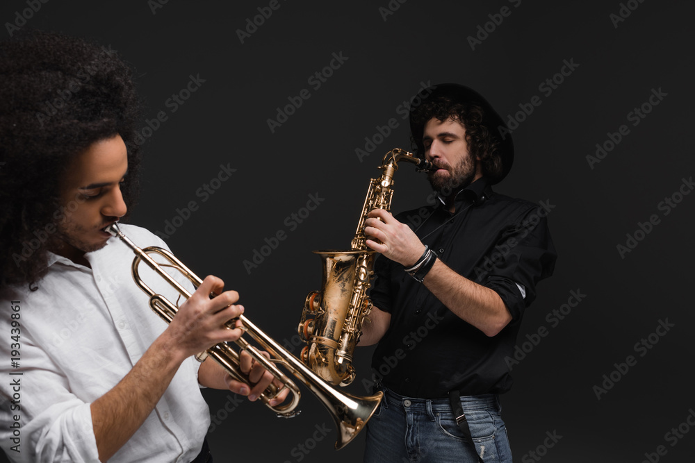 Fototapeta premium duet of musicians playing trumpet and saxophone on black