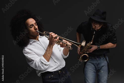 duet of musicians playing trumpet and sax on black