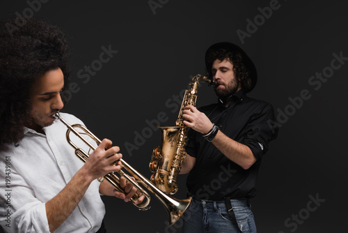 duet of musicians playing trumpet and saxophone on black