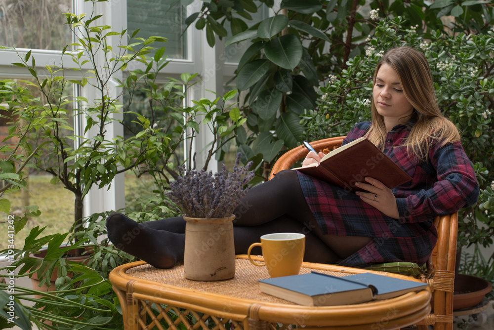 Beautiful young woman is writing her diary in winter garden Beautiful young woman is writing her diary in winter garden