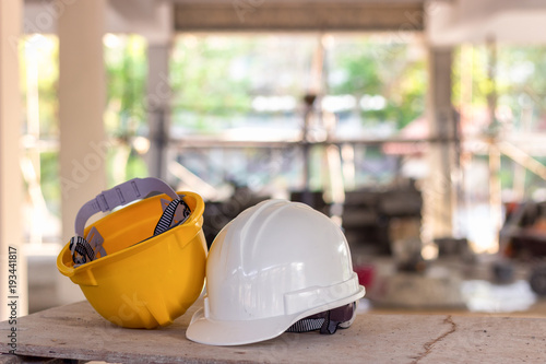 Yellow and white helmets are placed on the wooden table inside the construction area.