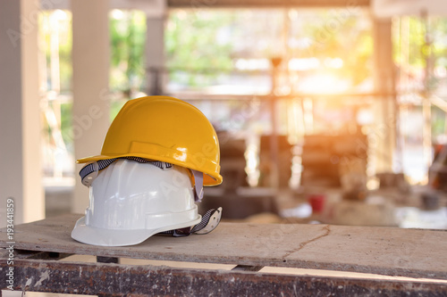 Yellow and white helmets are placed on the wooden table inside the construction area.
