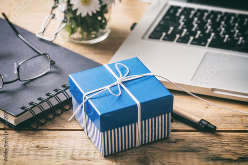 Blue gift box on an office desk, view from above