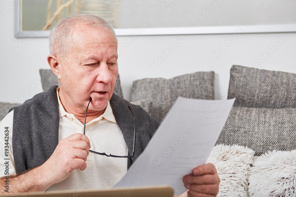 Senior als Rentner liest Unterlagen - obrazy, fototapety, plakaty 