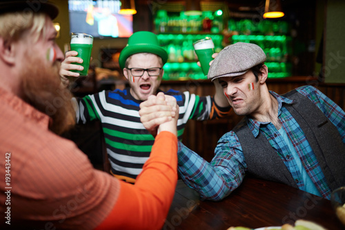 One of strong men winning his rival during armwrestling contest in pub