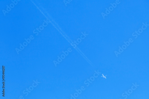 Jet plane with long trail in blue sky