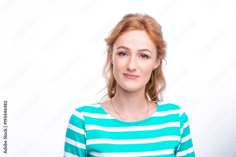 Close-up portrait of a young, beautiful woman with red curly hair in a summer dress with strips of blue in the studio on a gray background. Theme of summer vacation, tourism and summer clothes Close-up portrait of a young, beautiful woman with red curly hair in a summer dress with strips of blue in the studio on a gray background. Theme of summer vacation, tourism and summer clothes