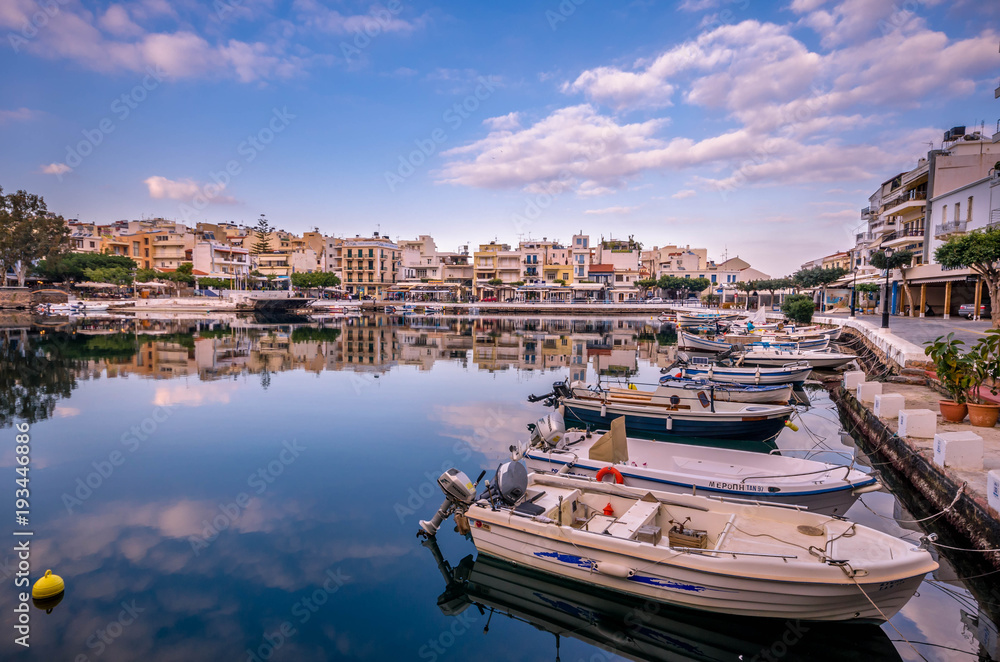 Agios Nikolaos Crete -Amazing view with reflections at Voulismeni lake. Dramatic sky with colorful buildings of one of the most popular touristic destination of Crete.