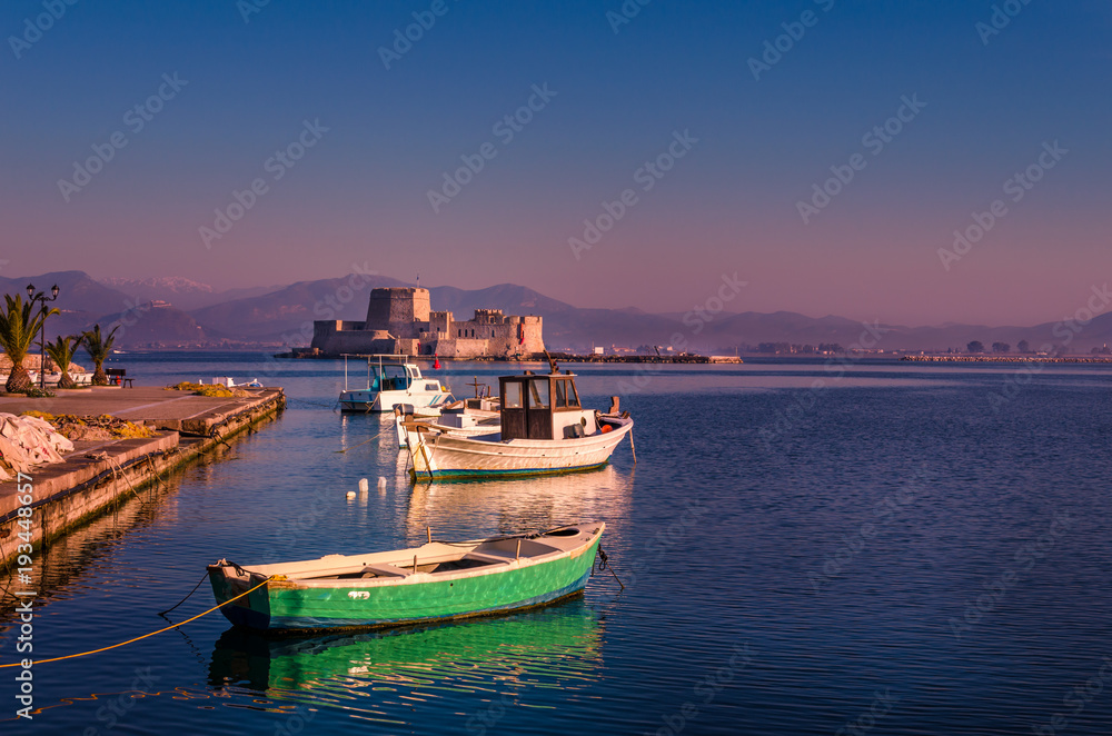 The historical water castle of Bourtzi on the background and small wooden fishing boats on the foreground.