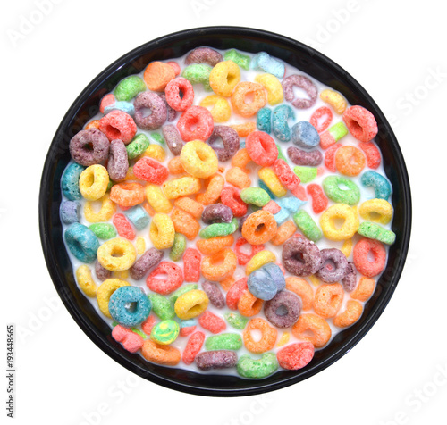 Delicious and nutritious fruit cereal loops flavorful in black bowl and milk on white background, healthy and funny addition to kids breakfast