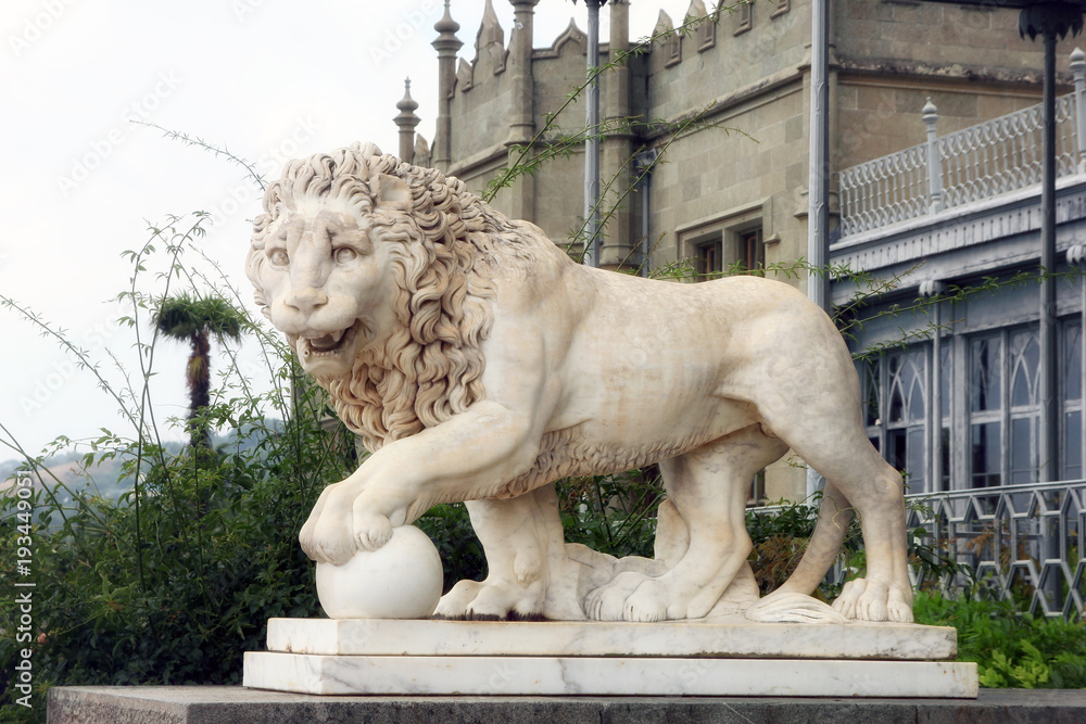 big old beautiful white marble statuary of lion with ball in Crimea