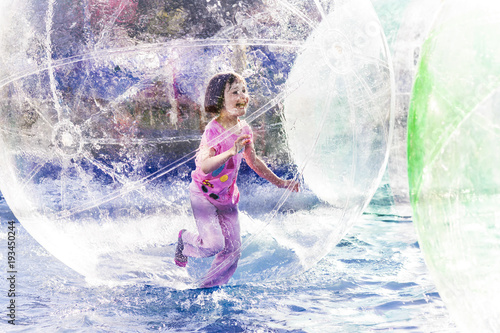 Young girl playing inside a floating water walking ball.