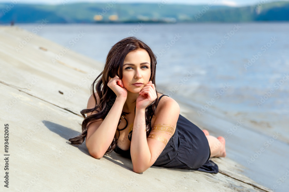 young beautiful girl lies on the river bank