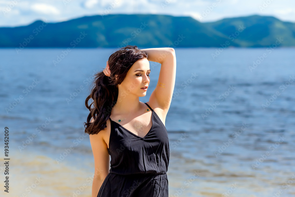 young beautiful girl stands on the background of water and mountains young beautiful girl stands on the background of water and mountains