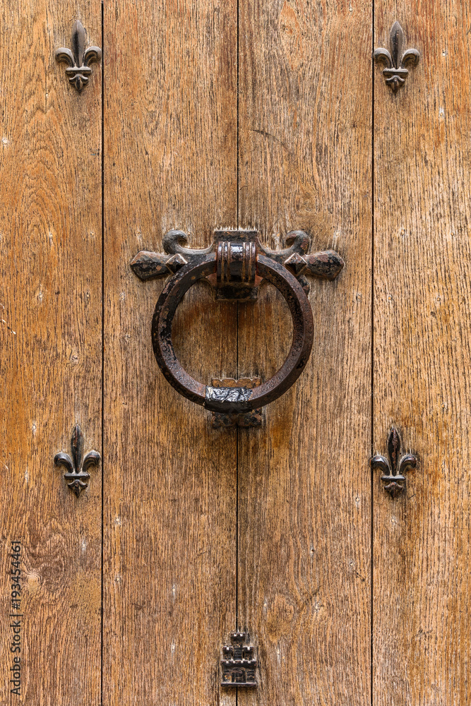 Ancient wooden entrance door with handle and fleur-de-lis ironwork. Saint-Denis, France Ancient wooden entrance door with handle and fleur-de-lis ironwork. Saint-Denis, France