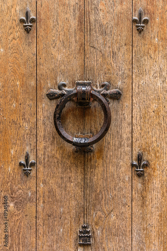 Ancient wooden entrance door with handle and fleur-de-lis ironwork. Saint-Denis, France