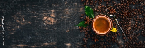 Hot espresso coffee in a cup. Cinnamon. On a black wooden background. Top view. Copy space.