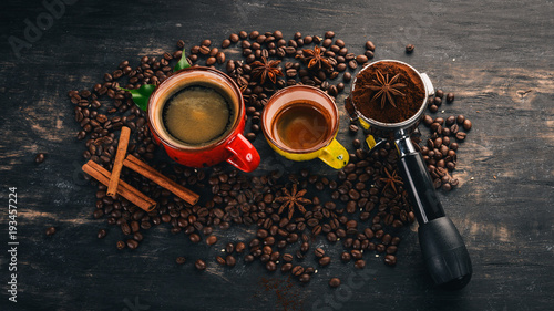 Two fragrant hot cup of coffee. Cinnamon. On a black wooden background. Top view. Copy space.