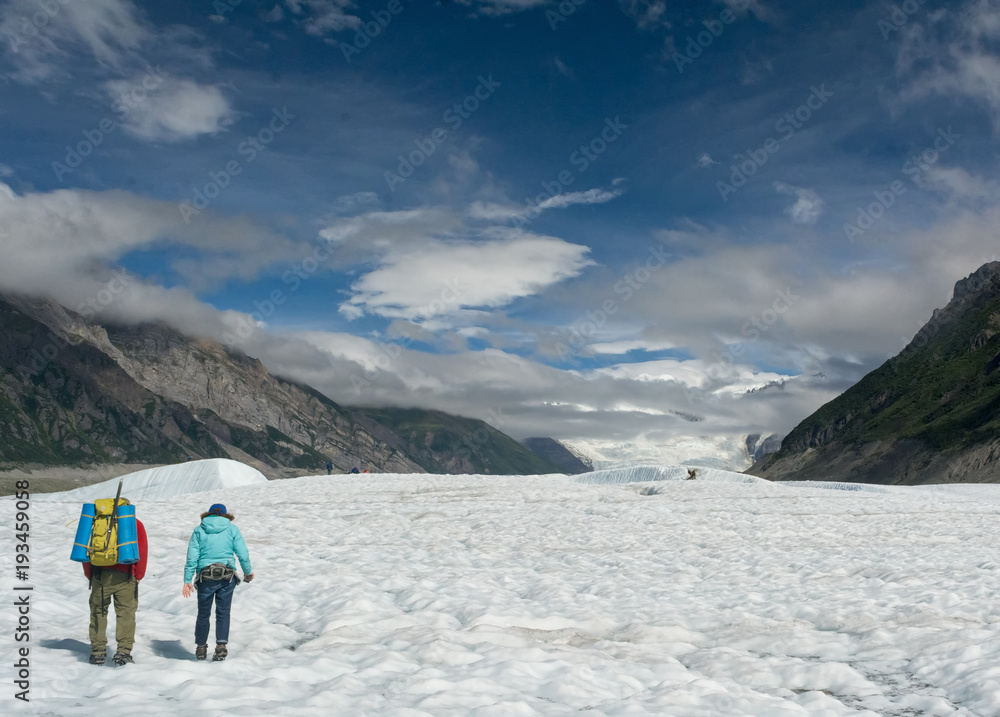 Two hikers walk on Root Glacier in Alaska