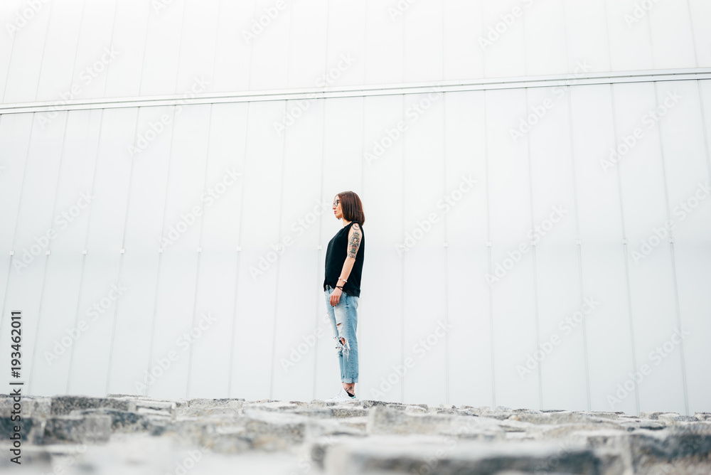 Young woman with tattoos standing on pavement Young woman with tattoos standing on pavement