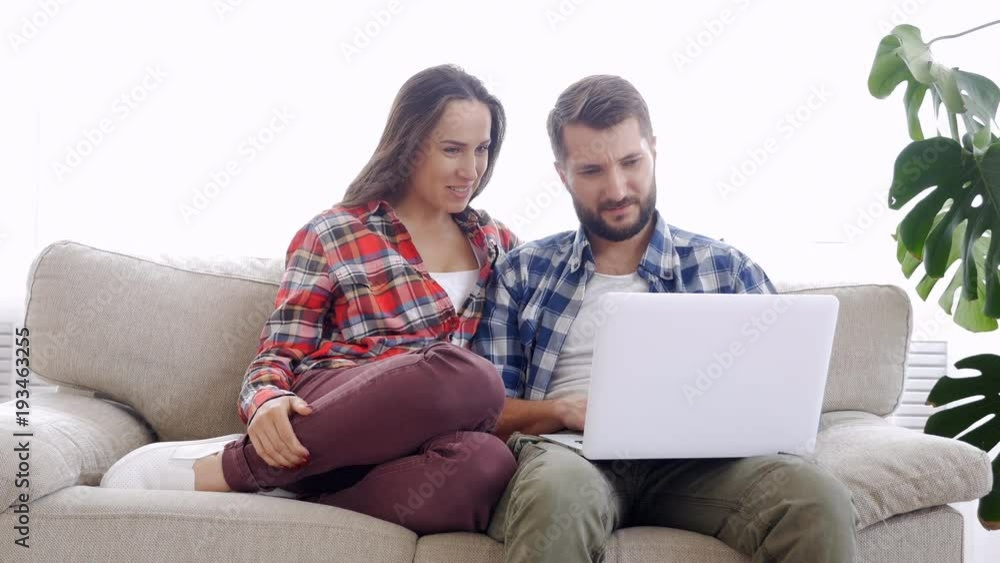 Loving couple sitting on sofa and using laptop Loving couple sitting on sofa and using laptop