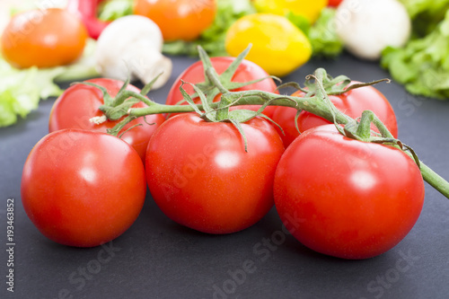 Tomatoes on the table. Red tomatoes lie on the old table. Dietary food. Tomatoes on the table on the background of vegetables.