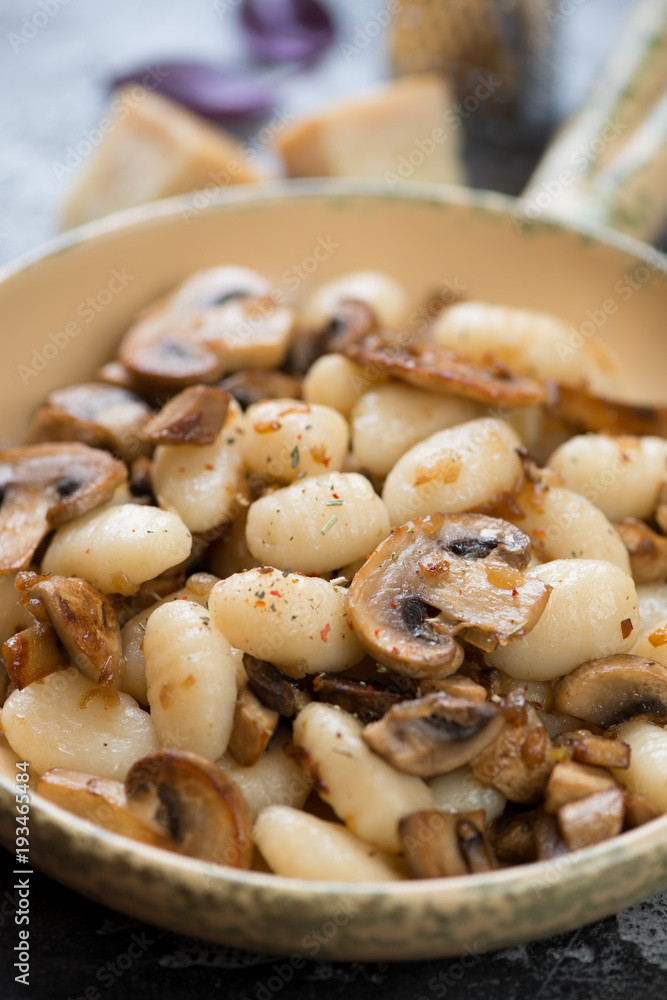 Close-up of italian potato gnocchi served with fried champignons, selective focus, vertical shot