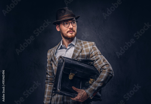 Foto A bearded man wearing casual suit in a hat and glasses holds sui