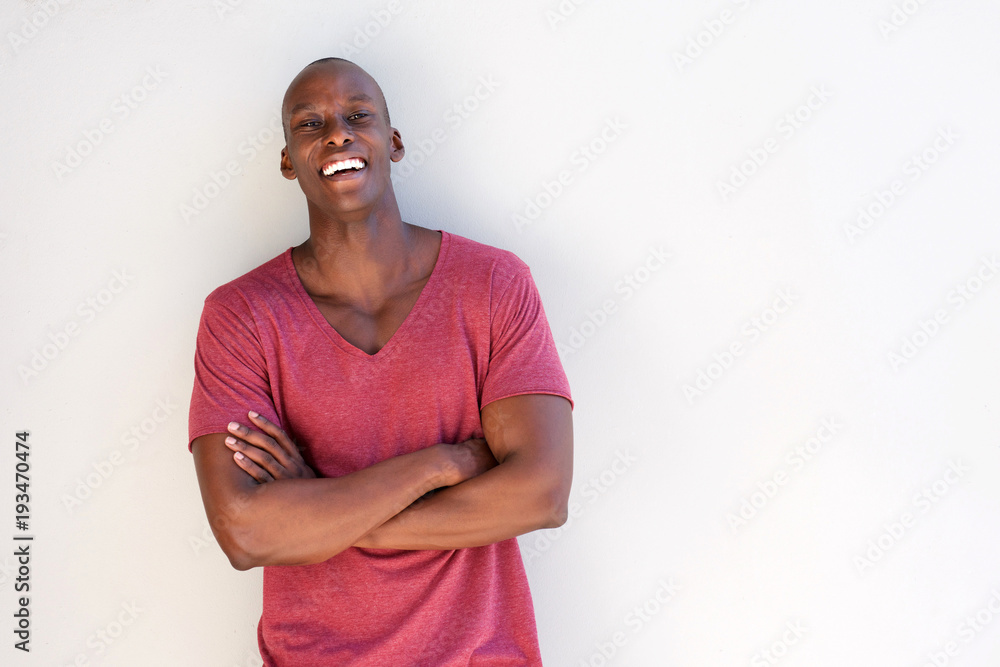 happy young black man smiling against white wall happy young black man smiling against white wall