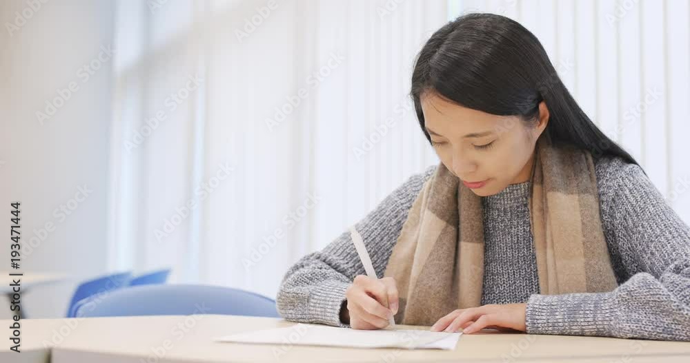 Student writing on note and doing revision in library Student writing on note and doing revision in library