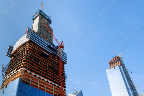Photography Construction cranes on construction site build office skyscraper building in New York City at sunset time