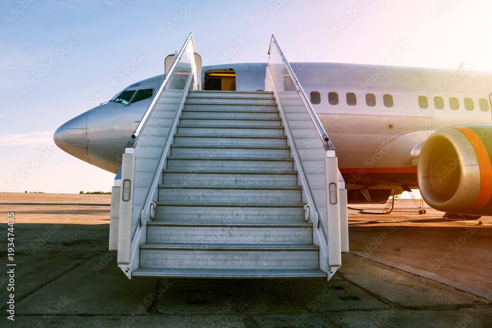 Fototapeta premium Pasażerski samolot z abordażu krokami w ranku słońcu