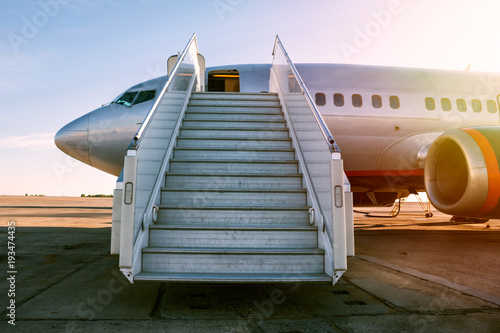 Passenger airplane with a boarding steps in the morning sun photo