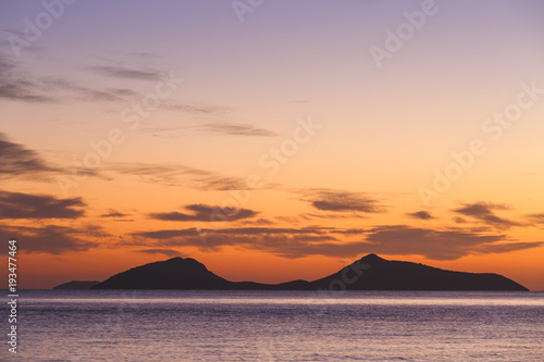 View of Trikeri island against colorful morning sky from Spetses, Greece. 