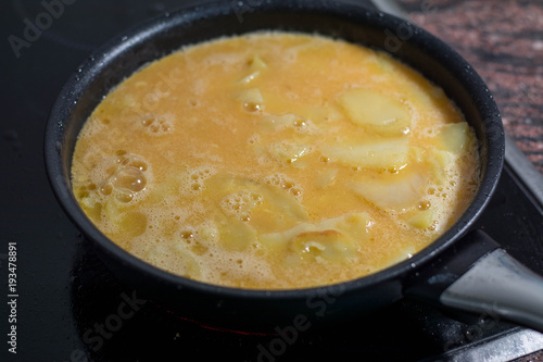 blended eggs and cut potatoes, making spanish omelette, Spanish tortilla, an omelette tortilla de patata, a typical Spanish dish of eggs, potatos, onions and olive oil.