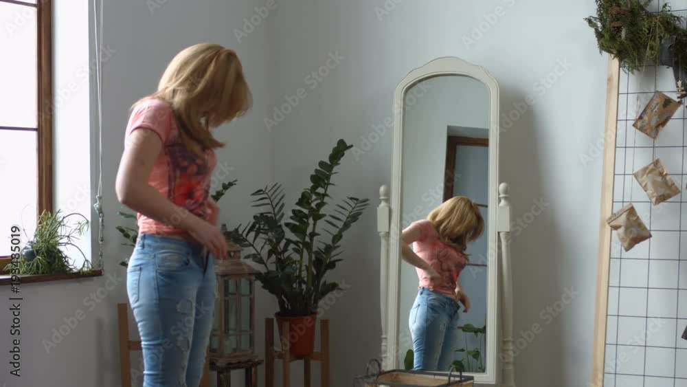 Attractive redhead woman struggling pulling up tight jeans after ...