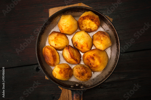 Fried potatoes in a frying pan on a wooden board photo