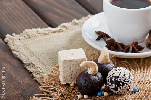 Chocolate sesame sweets and aromatic coffee with spices on an old wooden background.