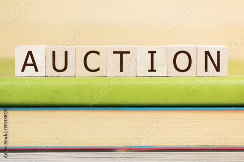 Auction word built with letter cubes on green book 