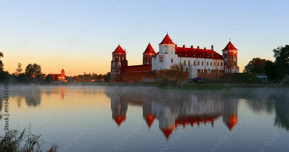 Mir, Belarus. Mir Castle Complex From Side Of Lake. Architectural Ensemble Of Feudalism, Ancient Cultural Monument. Famous Landmark. Misty Fog Above Lake In Summer Morning Mir, Belarus. Mir Castle Complex From Side Of Lake. Architectural Ensemble Of Feudalism, Ancient Cultural Monument. Famous Landmark. Misty Fog Above Lake In Summer Morning