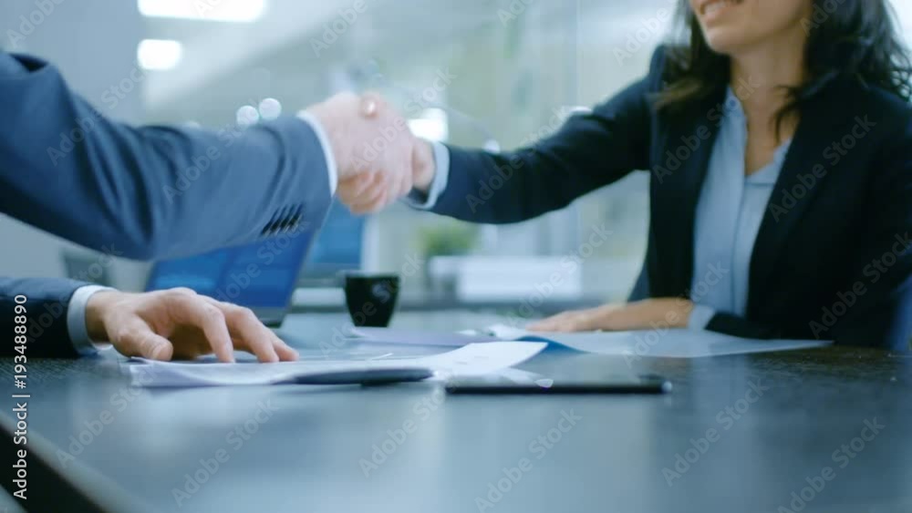 In the Office Close-up on Hands of Businesswoman and Businessman while Signing Contracts and Shaking Hands for Finishing Transaction. In the Office Close-up on Hands of Businesswoman and Businessman while Signing Contracts and Shaking Hands for Finishing Transaction.