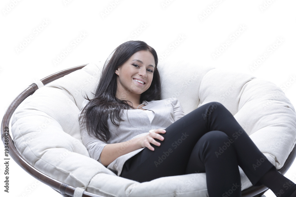 Modern young woman sitting in a round cozy soft chair Modern young woman sitting in a round cozy soft chair