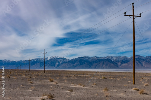 Electricity poles with mountains range in background on sunny day with big blue sky and white clouds, California road trip