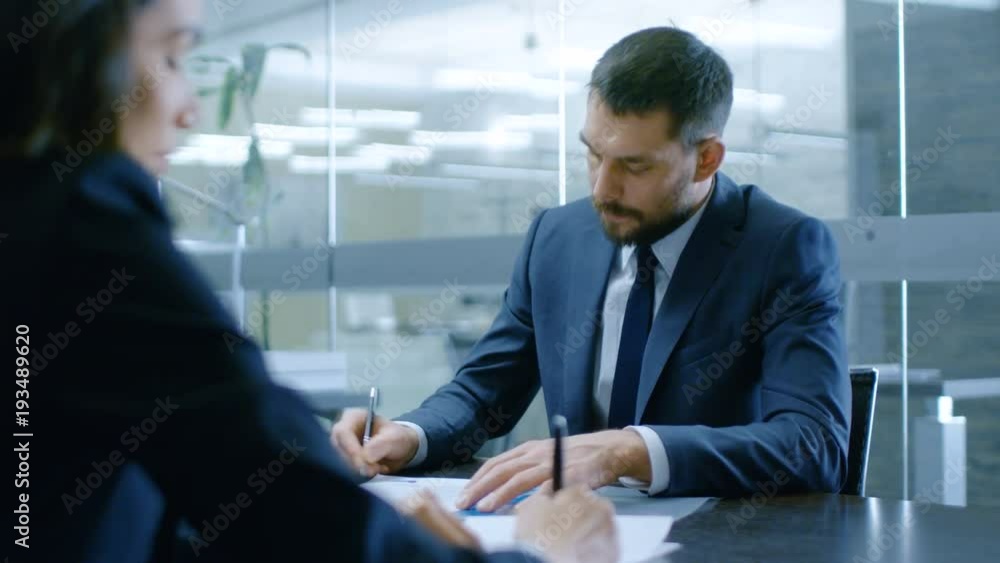 In the Office Businesswoman and Businessman Have Conversation, Negotianing, Draw up a Contract, Sign Documents, Finish Transaction, Shake Hands. Stylish People in Modern Conference Room. In the Office Businesswoman and Businessman Have Conversation, Negotianing, Draw up a Contract, Sign Documents, Finish Transaction, Shake Hands. Stylish People in Modern Conference Room.