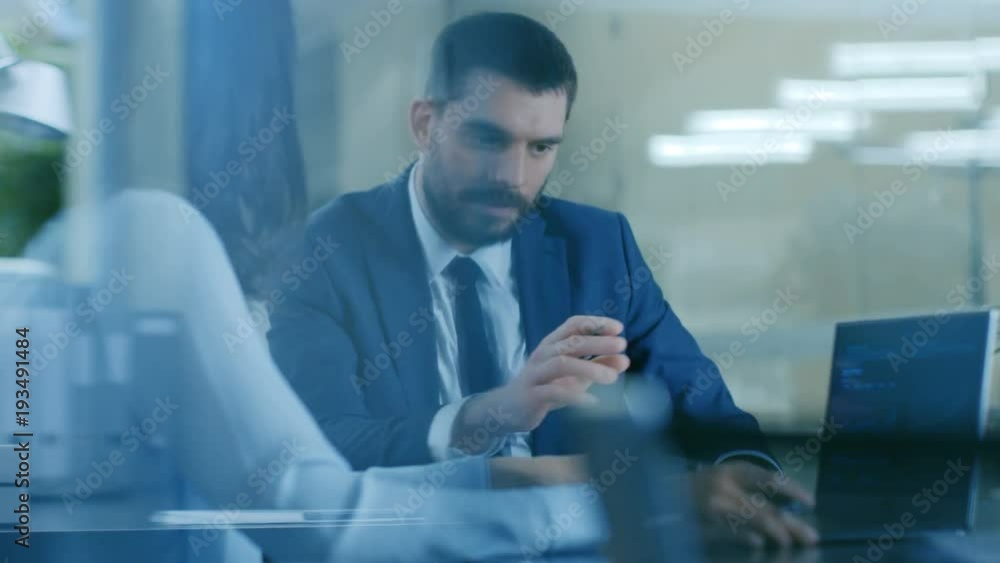 Beautiful Female Manager has Discussion with a Businessman sitting at His Desk. Working on a Laptop in Modern Office. Shot on RED EPIC-W 8K Helium Cinema Camera. Beautiful Female Manager has Discussion with a Businessman sitting at His Desk. Working on a Laptop in Modern Office. Shot on RED EPIC-W 8K Helium Cinema Camera.